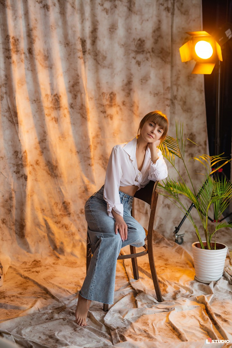 Студийный женский портрет со смешанным светом на тканевом фоне с пальмой