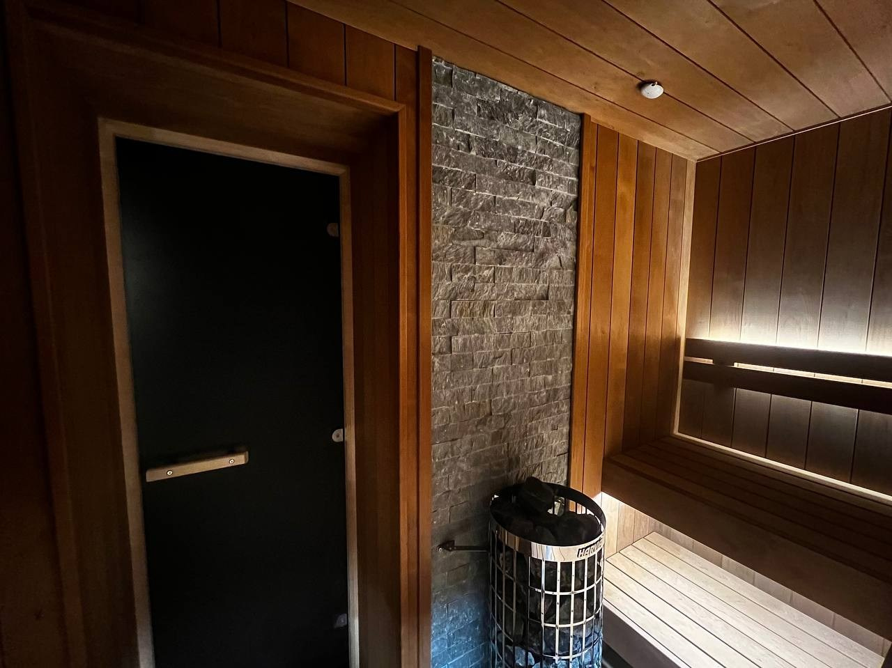 Семейная сауна на мансарде в Охта Парке: широкая термоольха, парящие полки и тёплая линейная подсветка для полного погружения. SaunaTopMasters