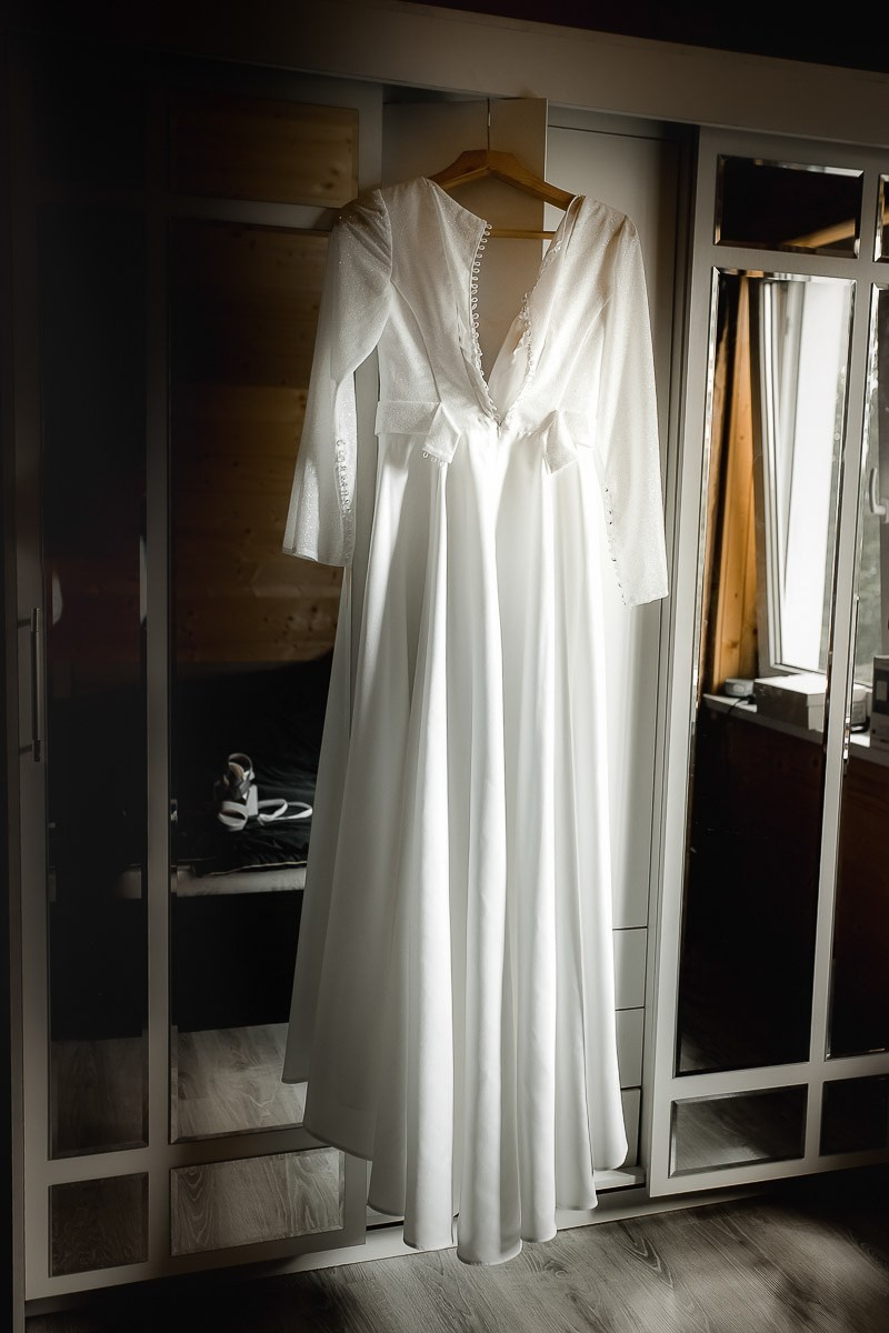 Свадебное белое платье висит на вешалке на дверце шкафа в комнате в Санкт-Петербурге
