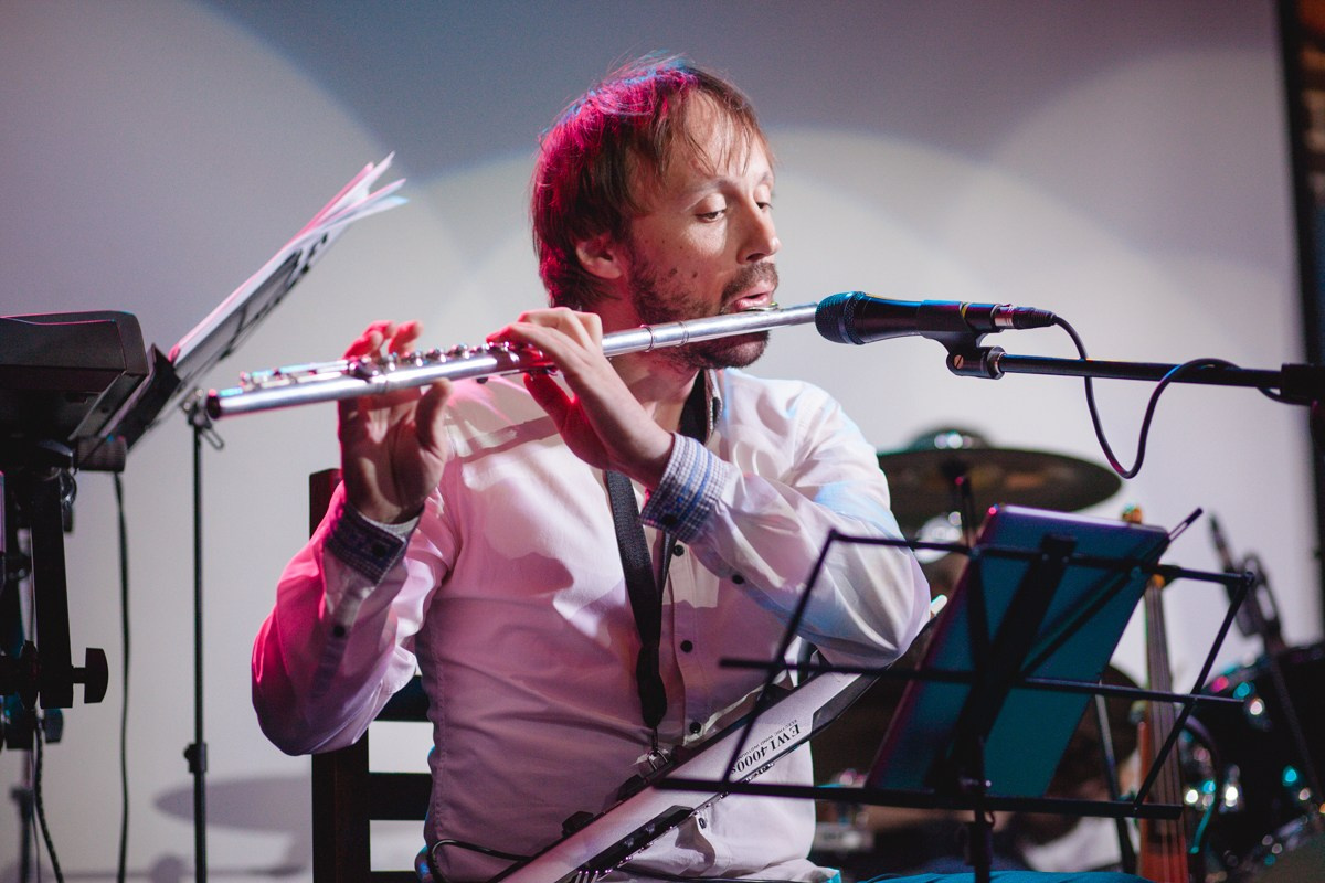 Флейтист мужчина играет на сцене бара Гластонбери