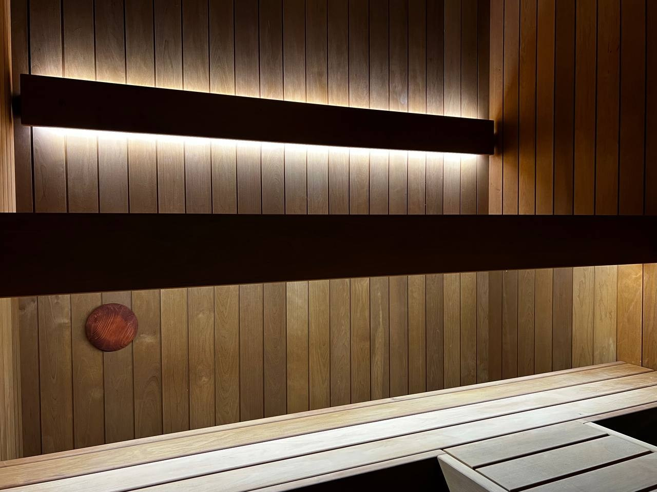 Компактная сауна в Охта Парке с электрокаменкой Harvia Cilindro, отделкой из термоольхи и сияющим можжевеловым панно. SaunaTopMasters
