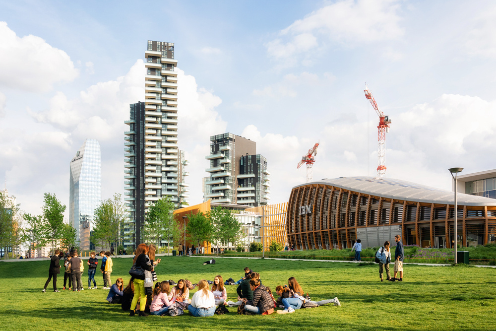 Milan, Italy. People relax in the sunny spring day in Biblioteca degli alberi park in Gae Aulenti square.