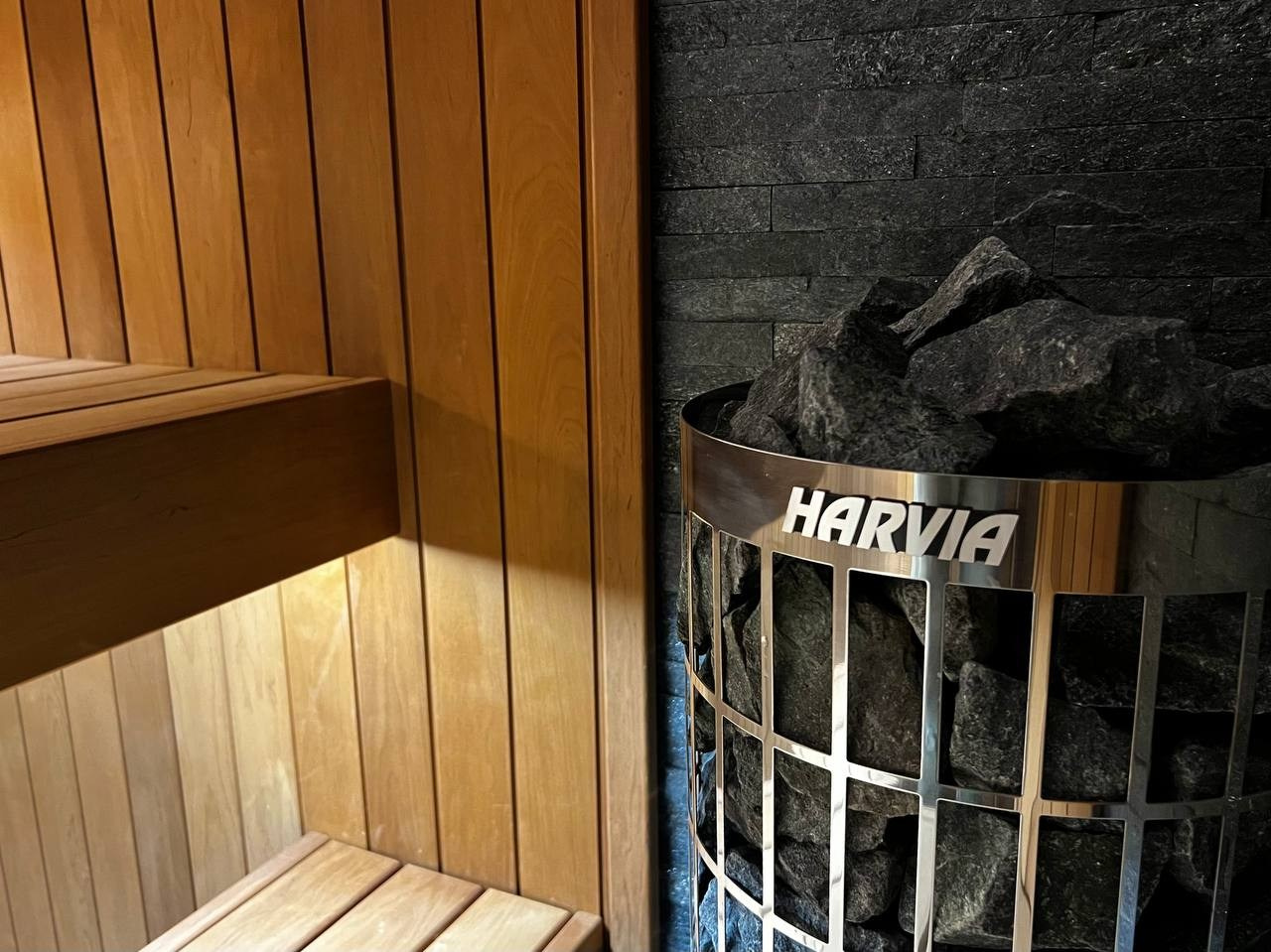 Компактная сауна в Охта Парке с электрокаменкой Harvia Cilindro, отделкой из термоольхи и сияющим можжевеловым панно. SaunaTopMasters