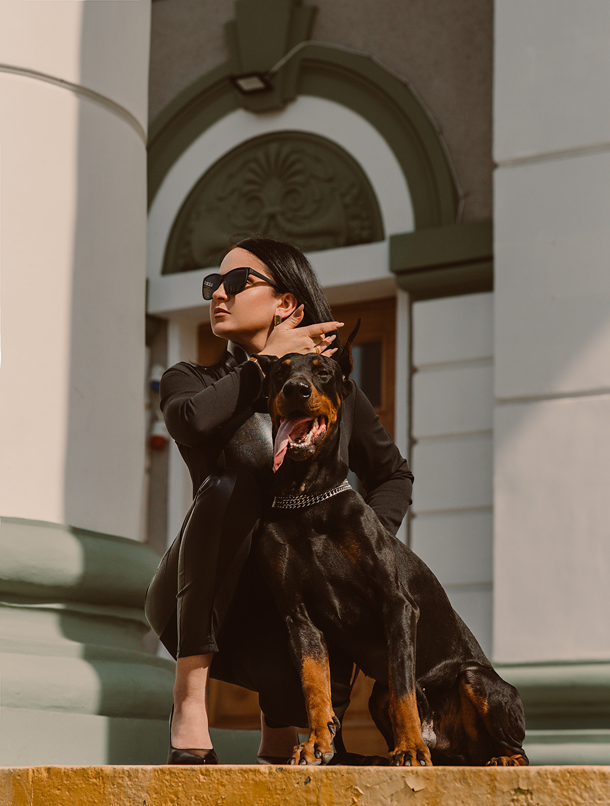 Фотосессия девушки с доберманом в черном костюме на площади