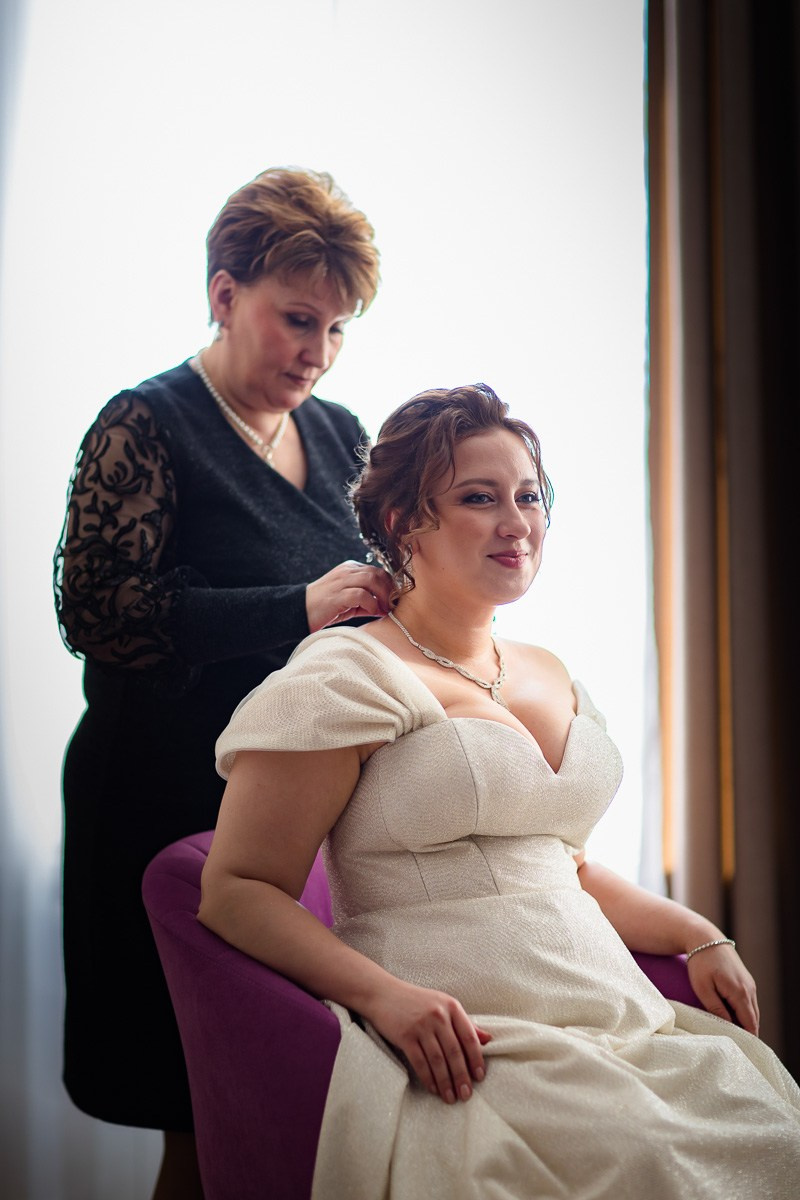 Мама невесты надевает ей украшение на шею