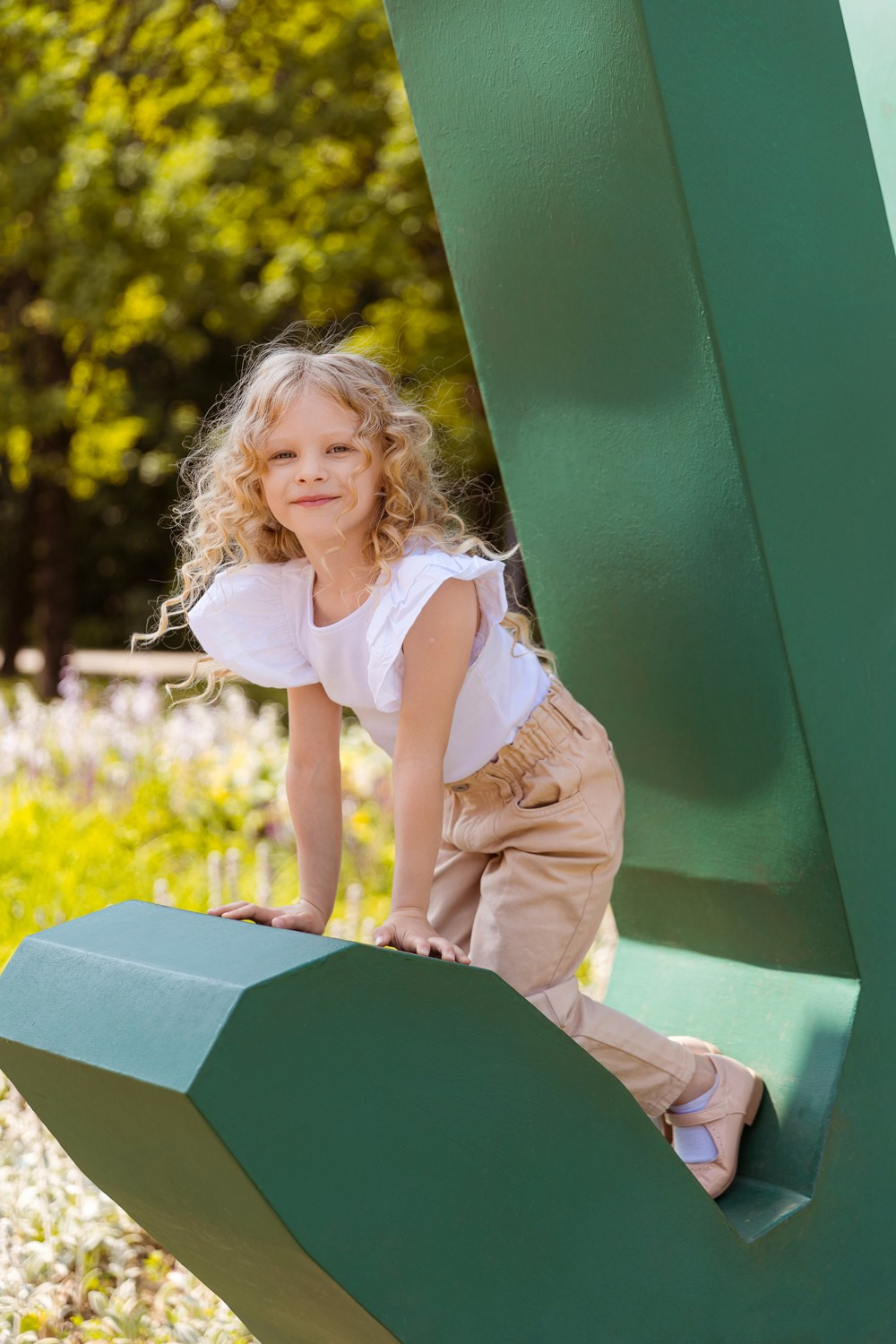 Девочка- кудряшка пересела на зеленую инсталляцию в виде руки.