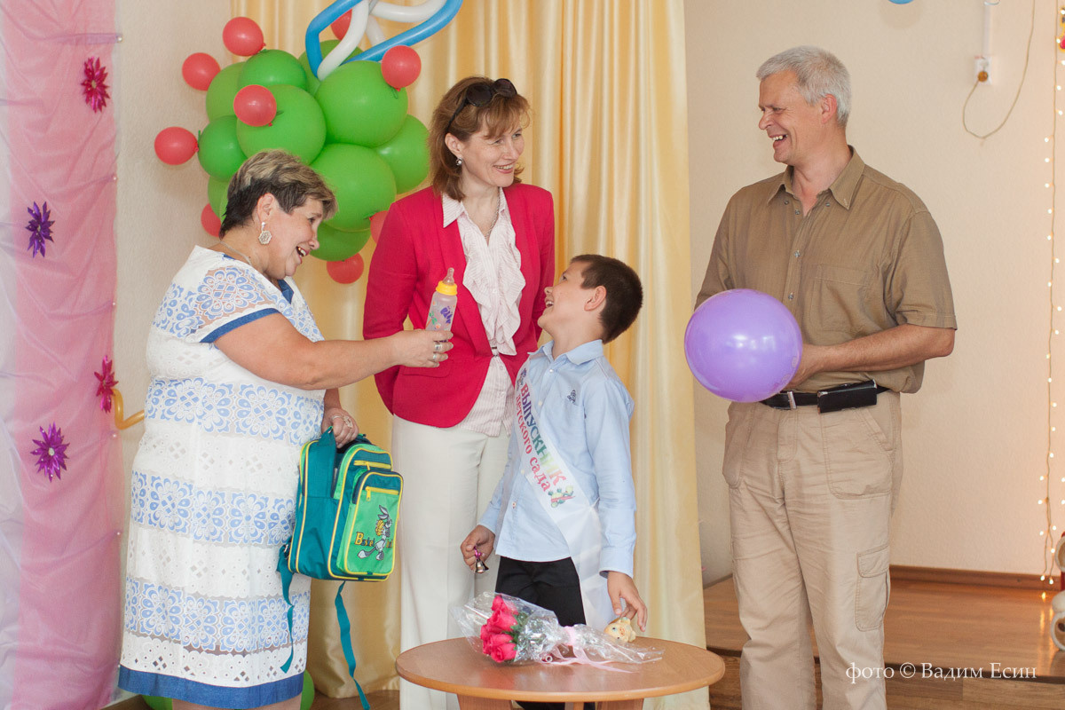 На выпускном утреннике заведующий вручает выпускнице детского сада выпускной альбом.