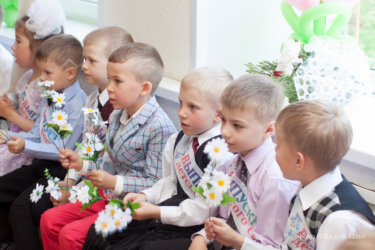 Выпускники детского сада сидят на стульях на выпускном в детском саду