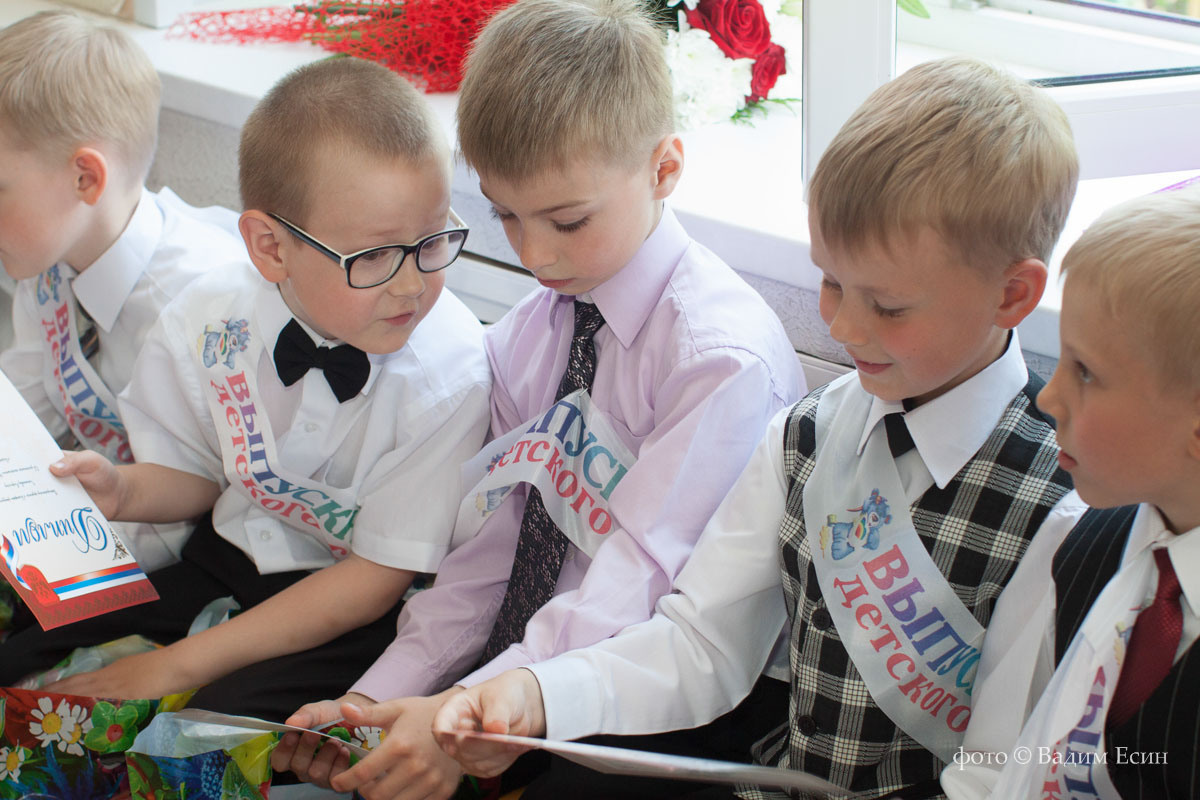 Выпускники рассматривают выпускной альбом на выпускном утреннике.