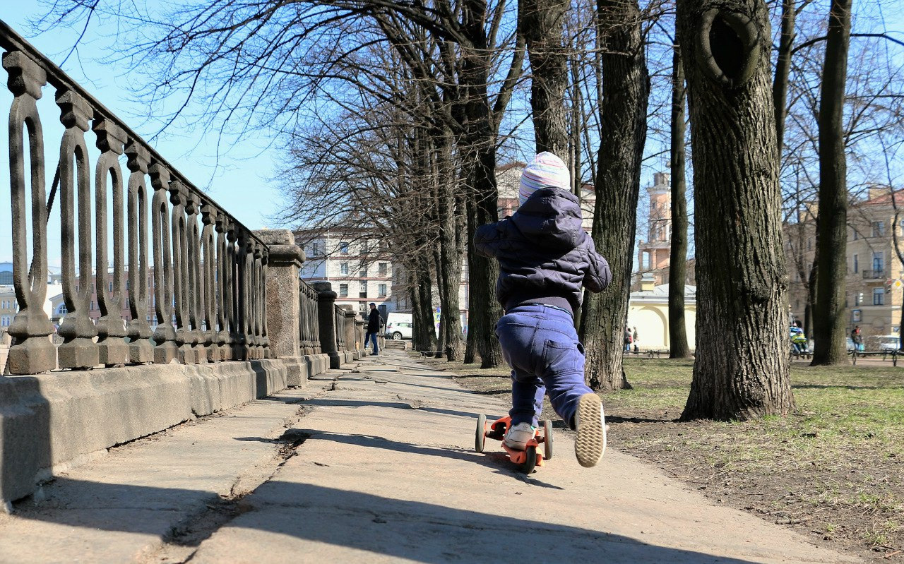 Мальчик на набережной едет на самокате