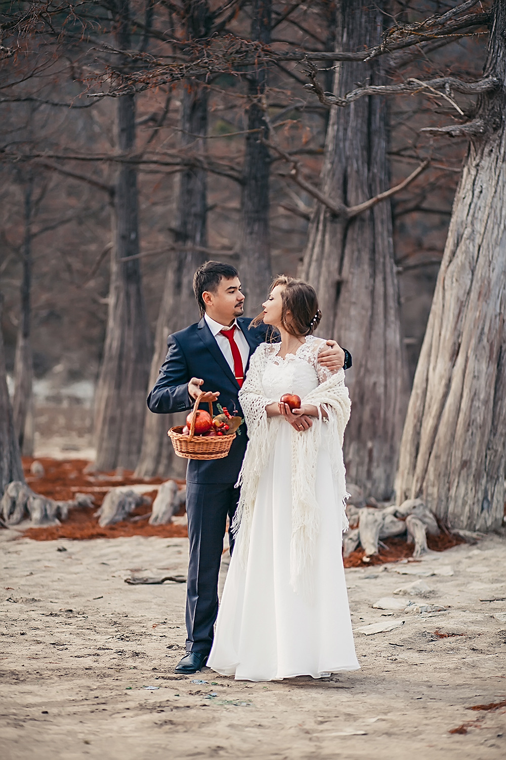 Жених и невеста стоят обнявшись в осеннем лесу