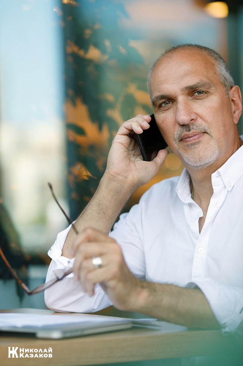 Портрет бизнесмена обсуждающего сделку по телефону , сидя за столиком в кафе