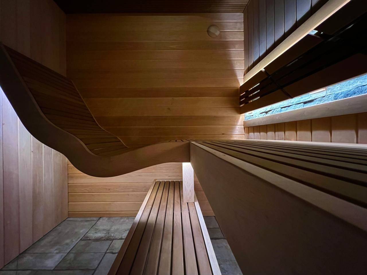 Парная в Лисьем носу с анатомическим пологом и можжевеловым панно, а хромированная печь в свете оптоволокна создает неповторимую атмосферу. SaunaTopMasters