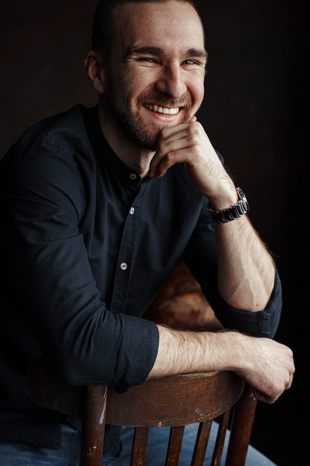 Молодой мужчина в черной рубашке улыбается