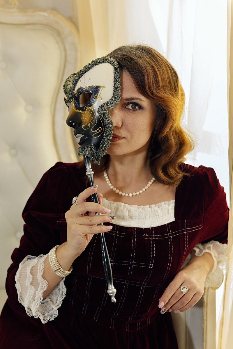 Профессиональный фотограф - портрет девушки в светлой студии с маской 