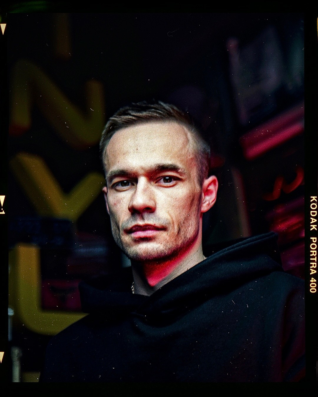 Парень на фоне жёлтых букв смотрит в объектив камеры