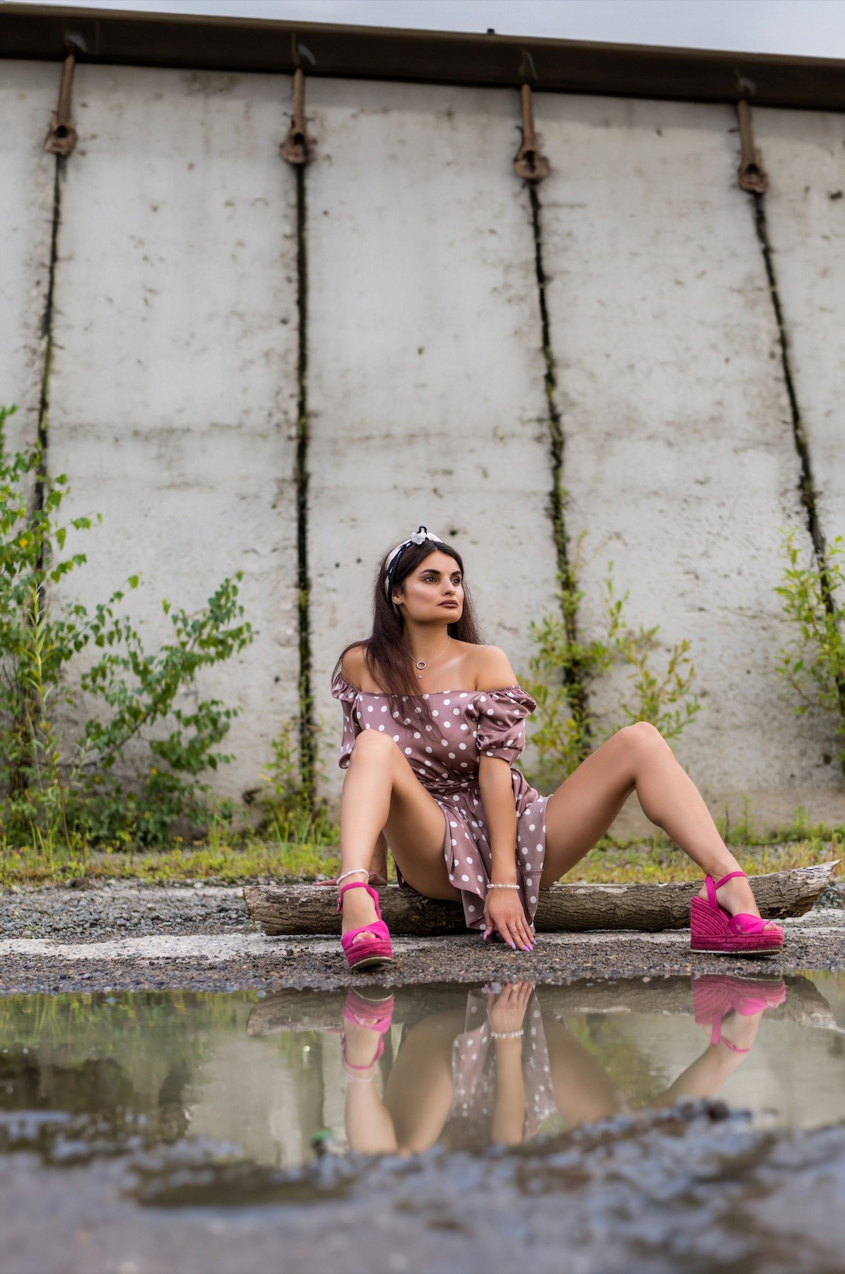 женщина  в платье сидит на земле около лужи, где видно ее отражение