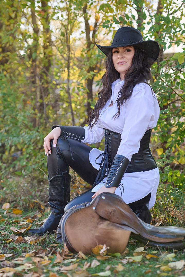 женщина в шляпе и кожаном корсете с седлом.