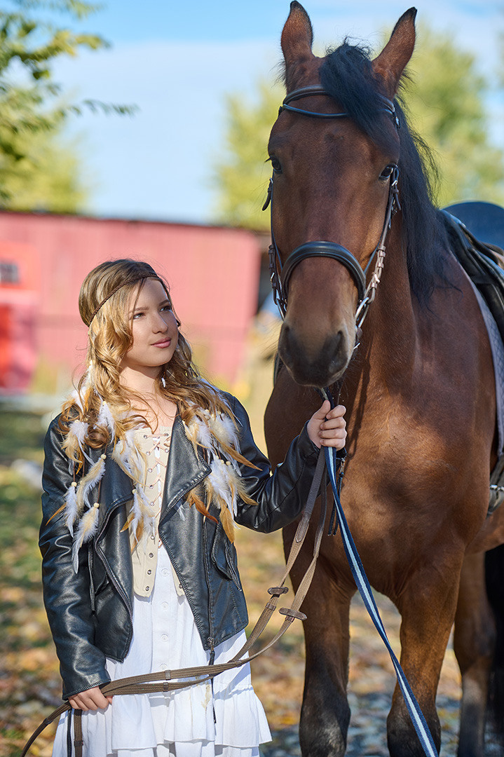 Девочка держит за узду коня.