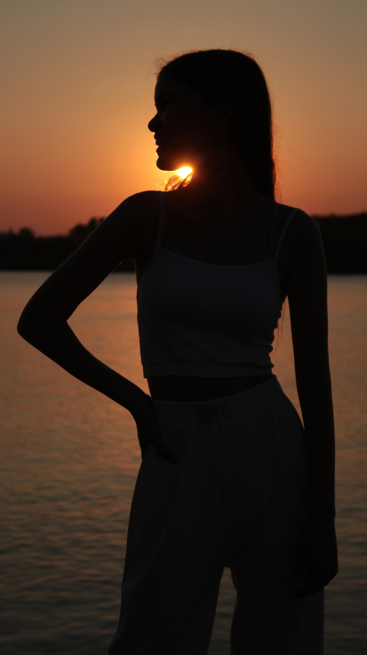 Силуэт девушки на фоне реки и заходящего солнца. Прогулочная съёмка.