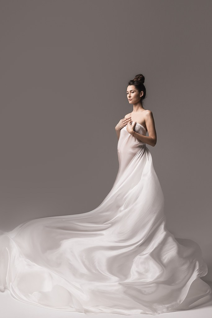 фотосессия беременной в фотостудии на светлом фоне в красивом разлетающемся платье, фотография беременности, фотосессия беременных, портрет беременной