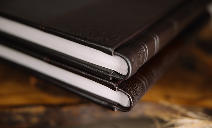Детальное фото торцов фотокниг в премиальном переплете из темно-коричневой кожи.