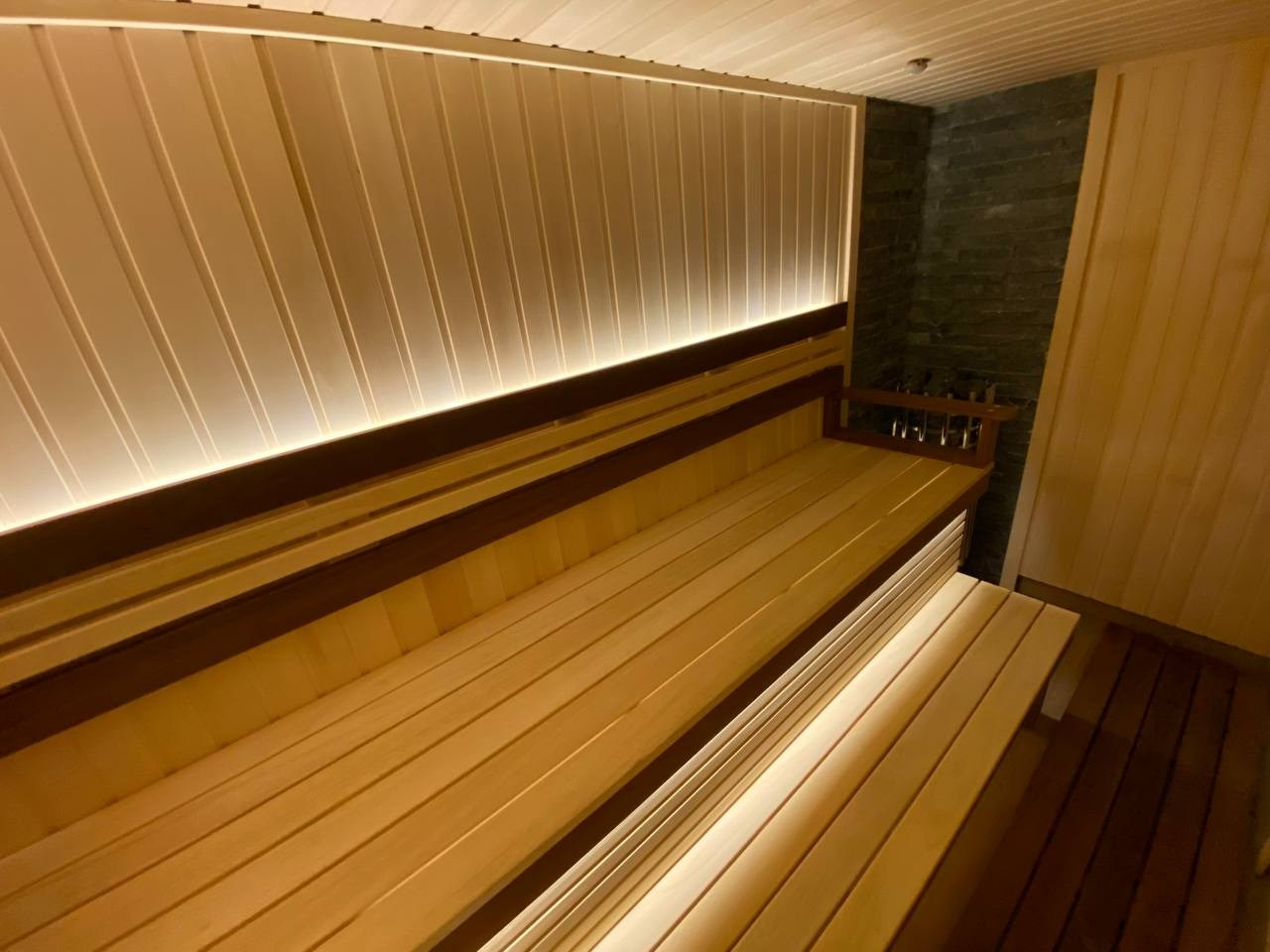 Семейная сауна в Кузьмолово на базе Harvia Glow. В отделку из липы встроены просторные полки из комбинации абаши+ термоабаши. SaunaTopMasters