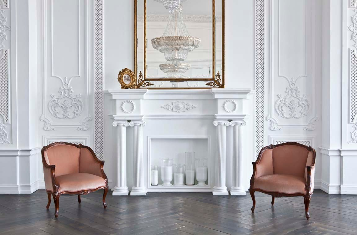 белый камин с белой стеной и двумя креслами на деревянном полу в фотостудии
