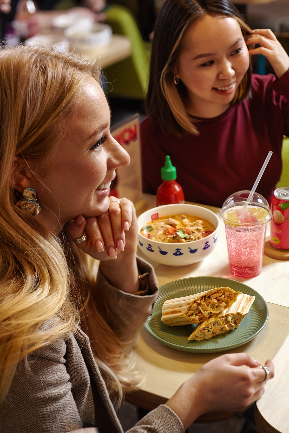 Две девушки сидят за столиком в ресторане Дед Хо, общаются и пробуют еду 