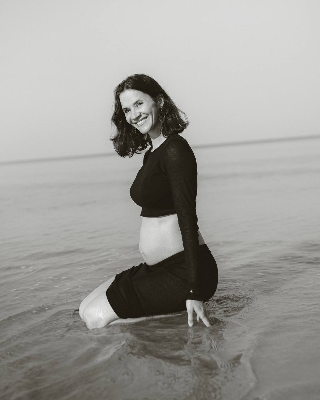 Девушка сидит в воде у моря в чёрно-белом кадре