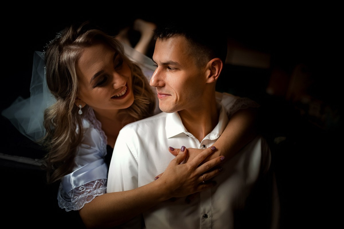 Невеста обнимает жениха сзади в комнате в Санкт-Петербурге.