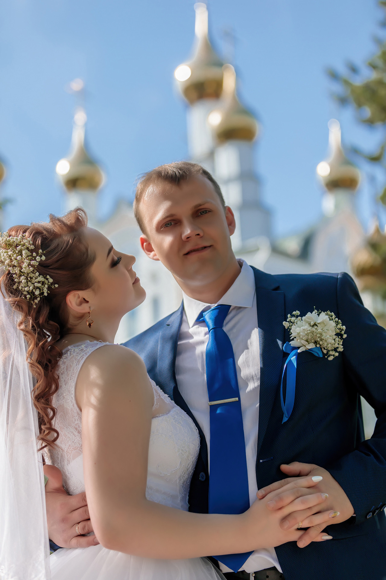 жених и невеста обнимаются в сквере на фоне церковных колоколов 