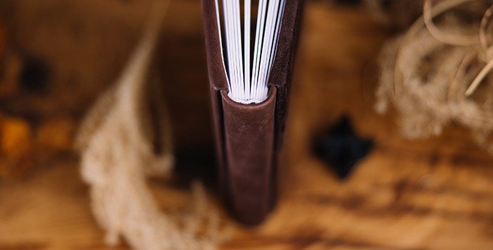 Торец фотокниги сверху: виден надежный переплет, плотность белых страниц и аккуратная стыковка материалов обложки на корешке.