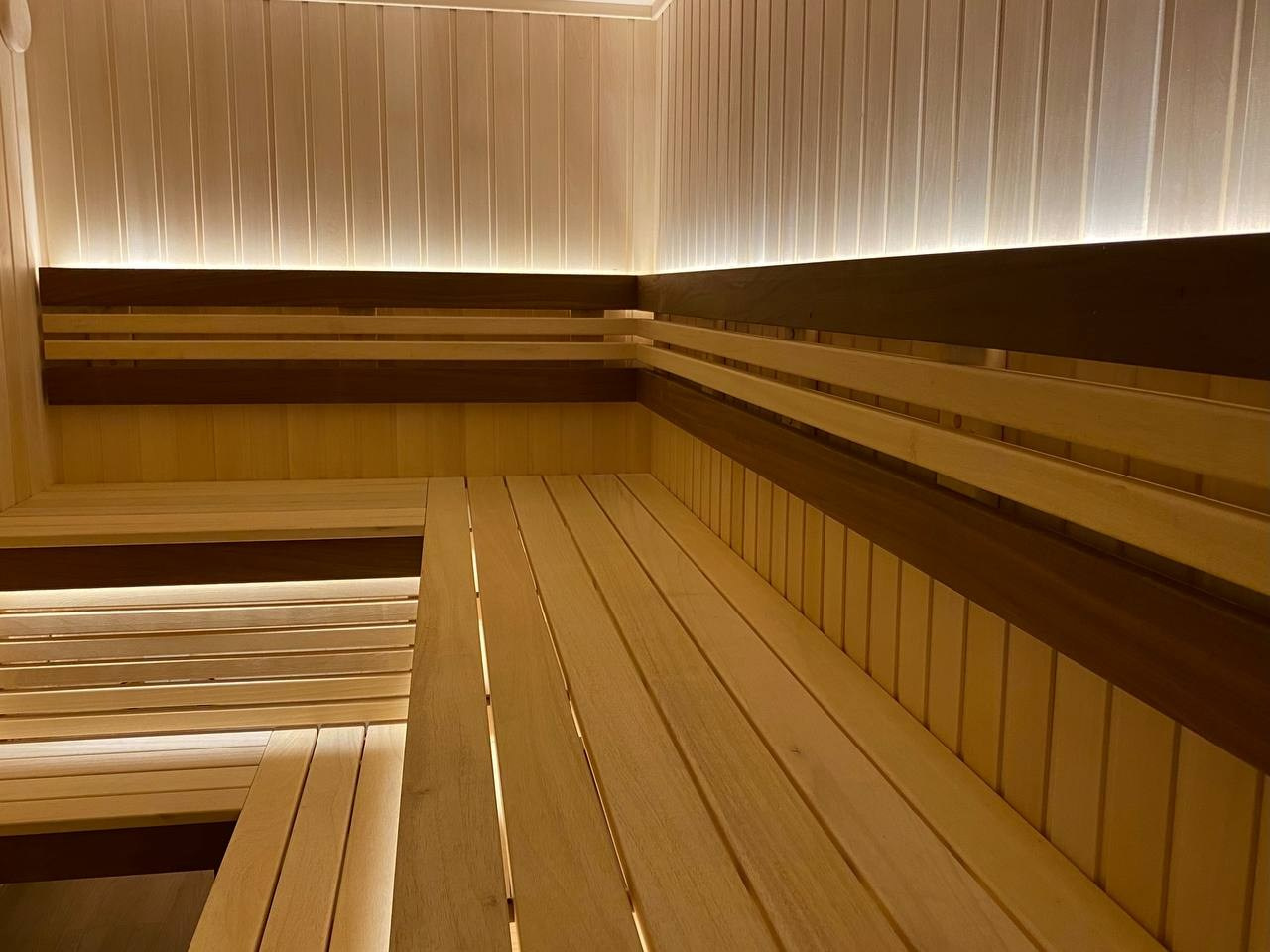Семейная сауна в Кузьмолово на базе Harvia Glow. В отделку из липы встроены просторные полки из комбинации абаши+ термоабаши. SaunaTopMasters