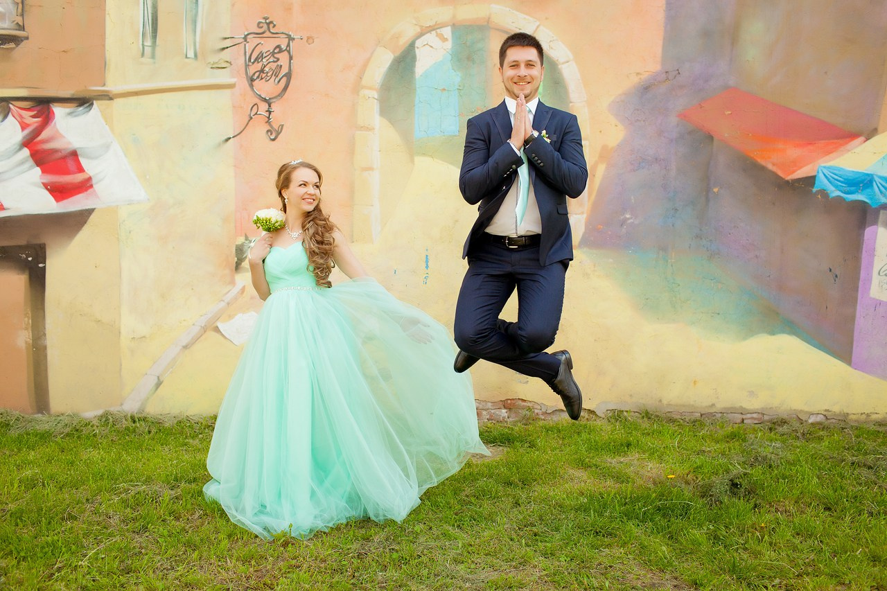 невеста в платье цвета тиффани и жених парящий в позе лотоса на фоне стены с граффити