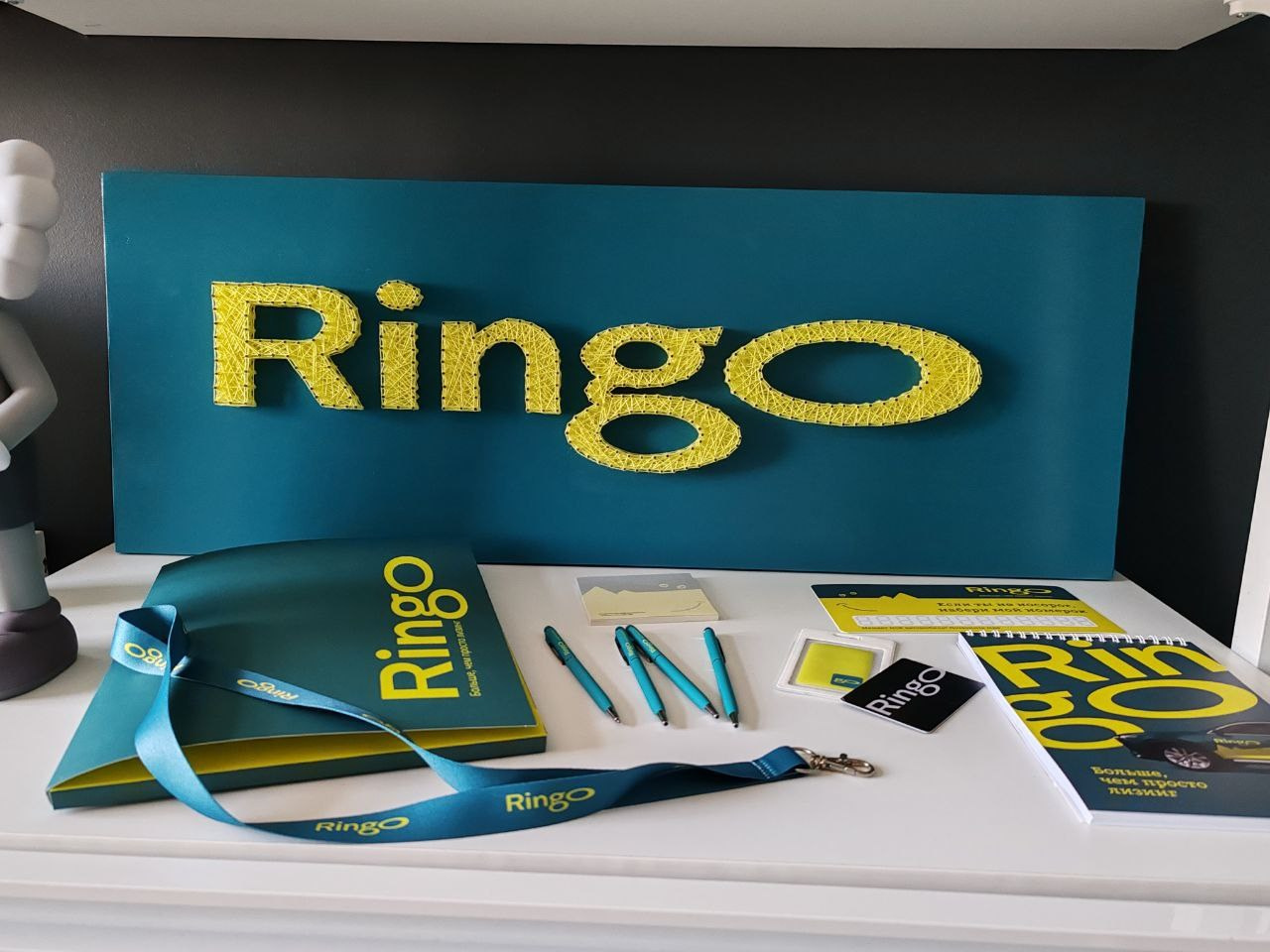 Логотип компании по лизингу желтыми нитками на бирюзовом фоне