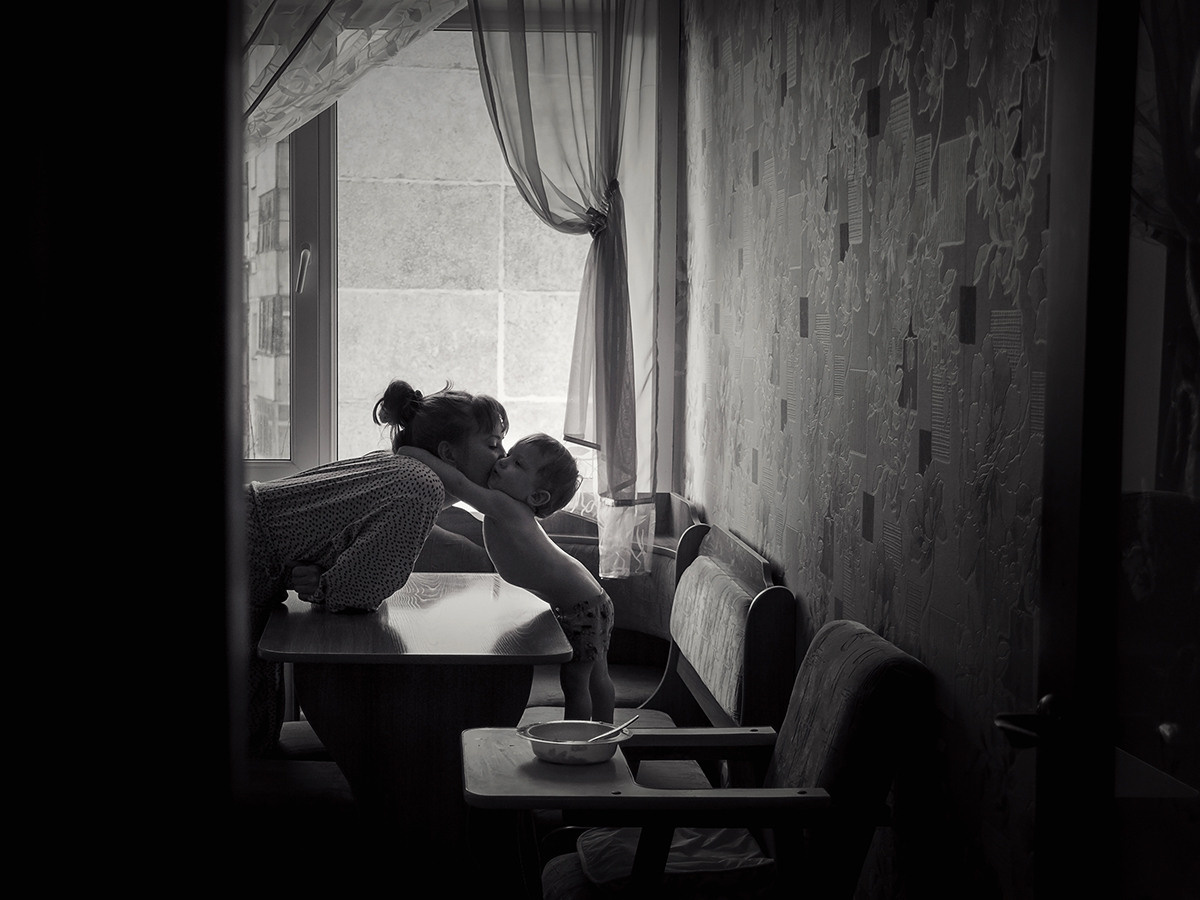 Мама и ребёнок в объятиях в домашней обстановке на кухне за столом, после завтрака.