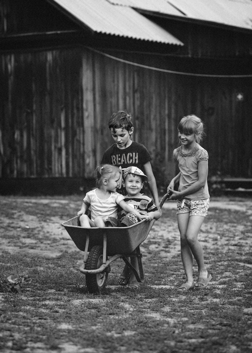 Веселая компания катается в железном совке летом в деревне у бабушки.