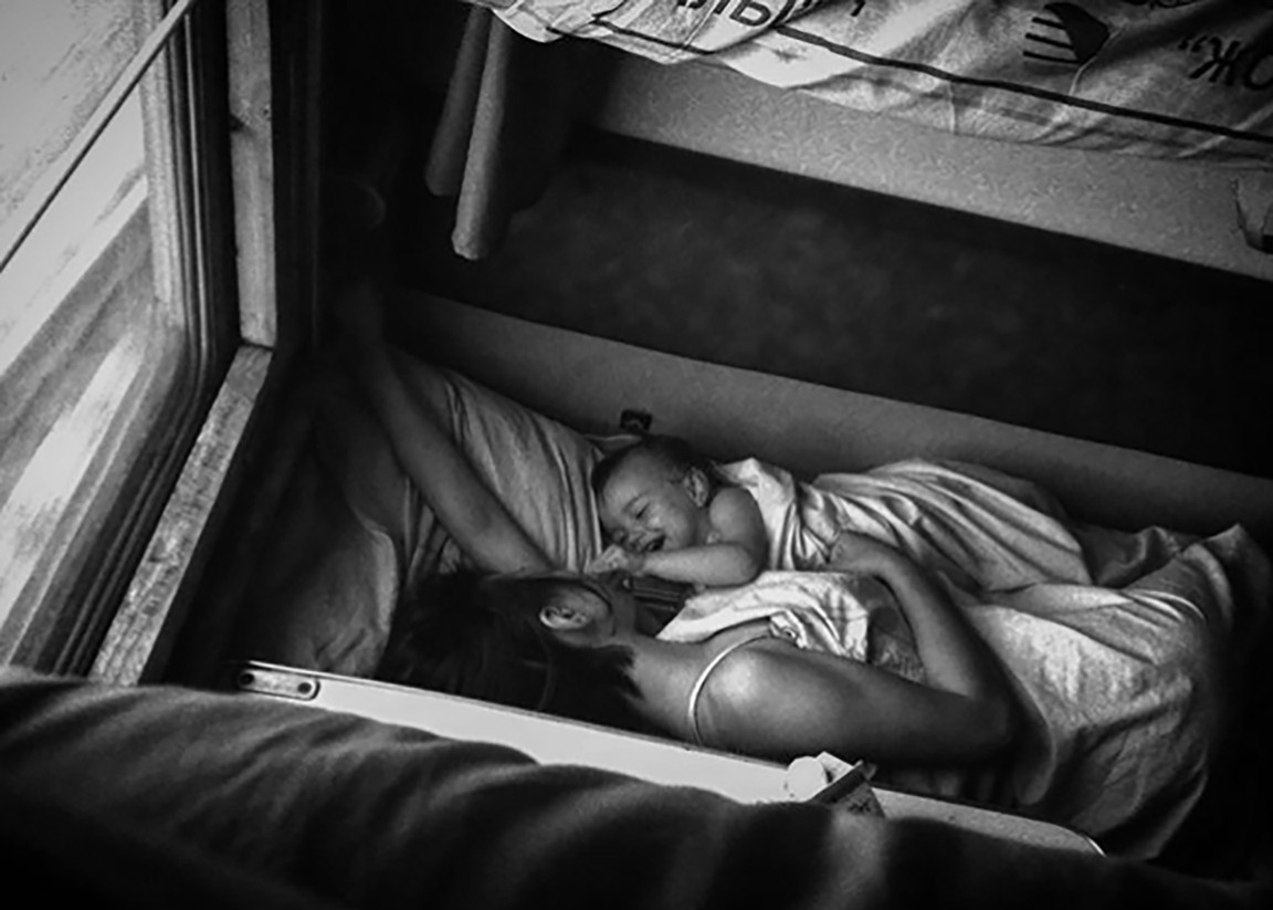 В поезде мама и  дочь развлекаются в дороге. Мама спит, ребенок веселится. 