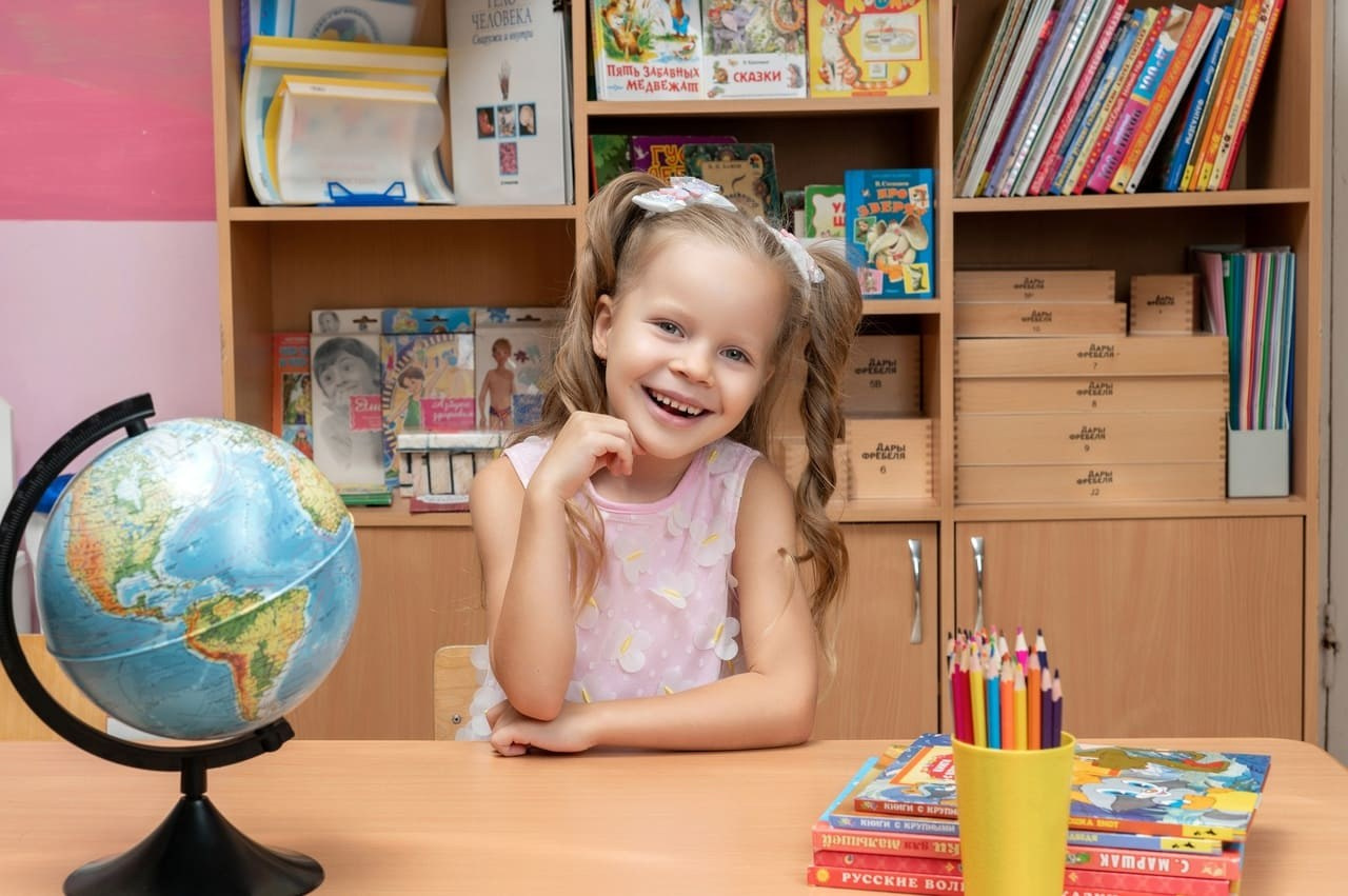 Девочка с косичками позирует фотографу на фотосессии в детском саду Челябинска.