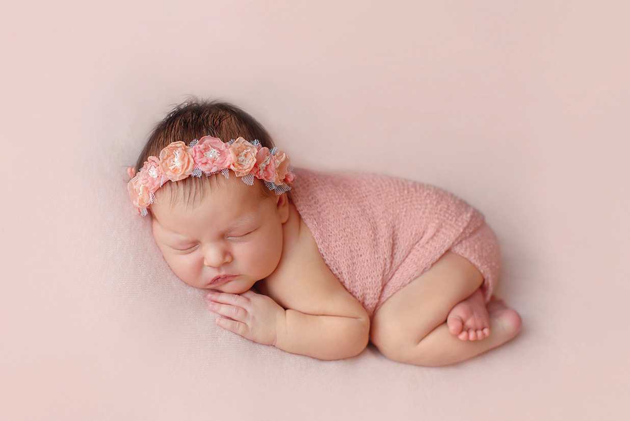 новорожденный лежит в базовой позировке у него веночек на голове