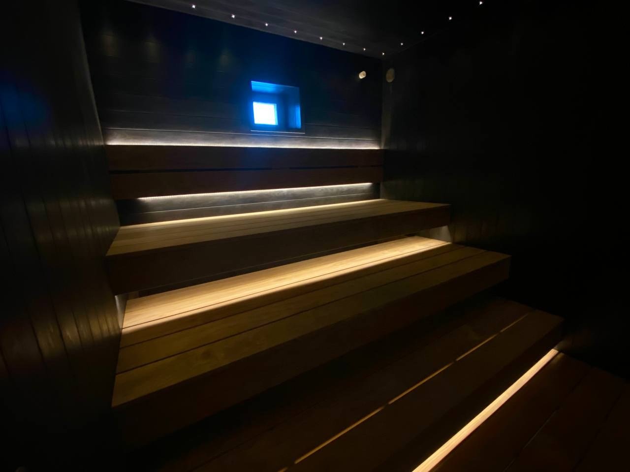 Чёрная «Богатырь-баня» в Боровске: четыре уровня полков, белый кварцит в противопожарном углу и кастомная газовая печь в центре внимания. SaunaTopMasters