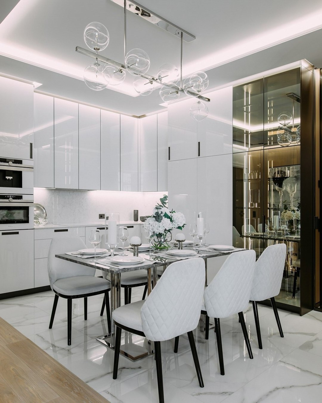 Просторная кухня-гостиная в белом цвете с дизайнерским светильником и мягкими стульями | Валерия Котович