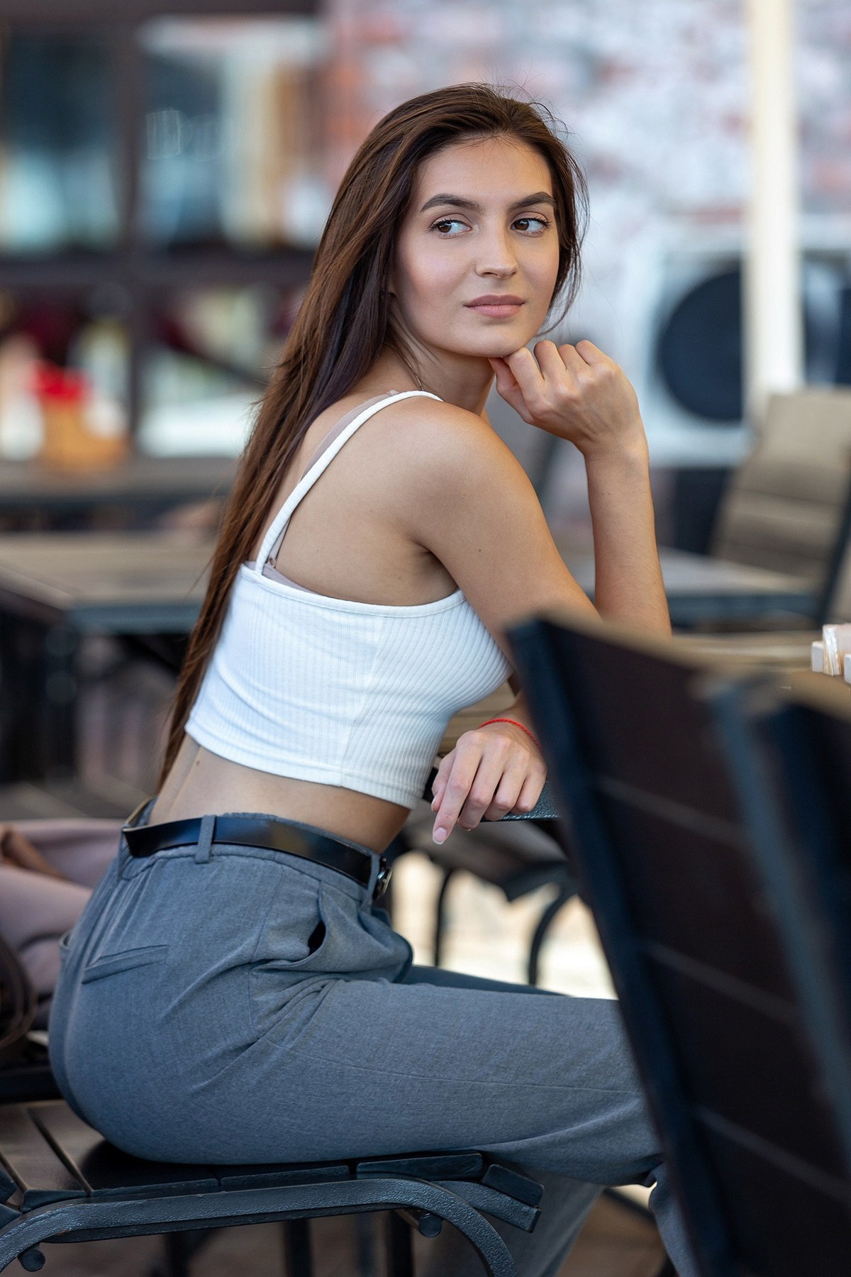 Портрет девушки в джинсах за столиком в летнем кафе