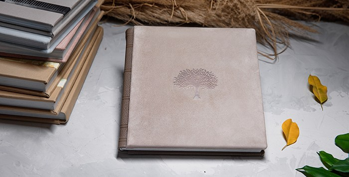 Вид сверху на эксклюзивную фотокнигу с тиснением и стопку альбомов из премиальных материалов.