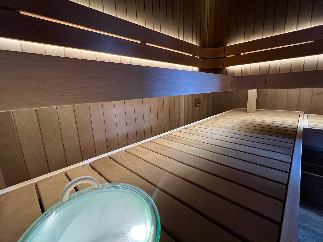 Парная в Колосе по индивидуальному проекту с реечным потолком, плавными линиями радиальных элементов и теплой закарнизной подсветкой. SaunaTopMasters