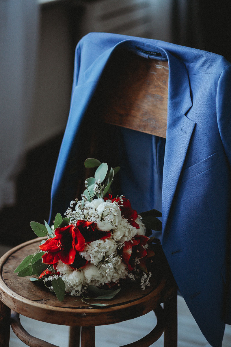 Свадебный букет невесты и пиджак жениха на стуле, съемка от окна в студии