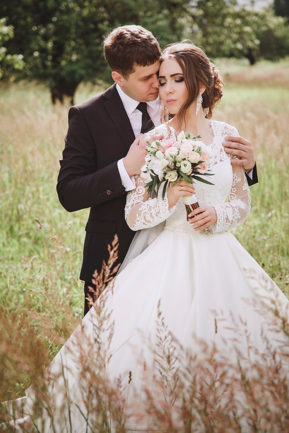 Красивое платье невесты, букет, съемка в траве у стен Свенского монастыря