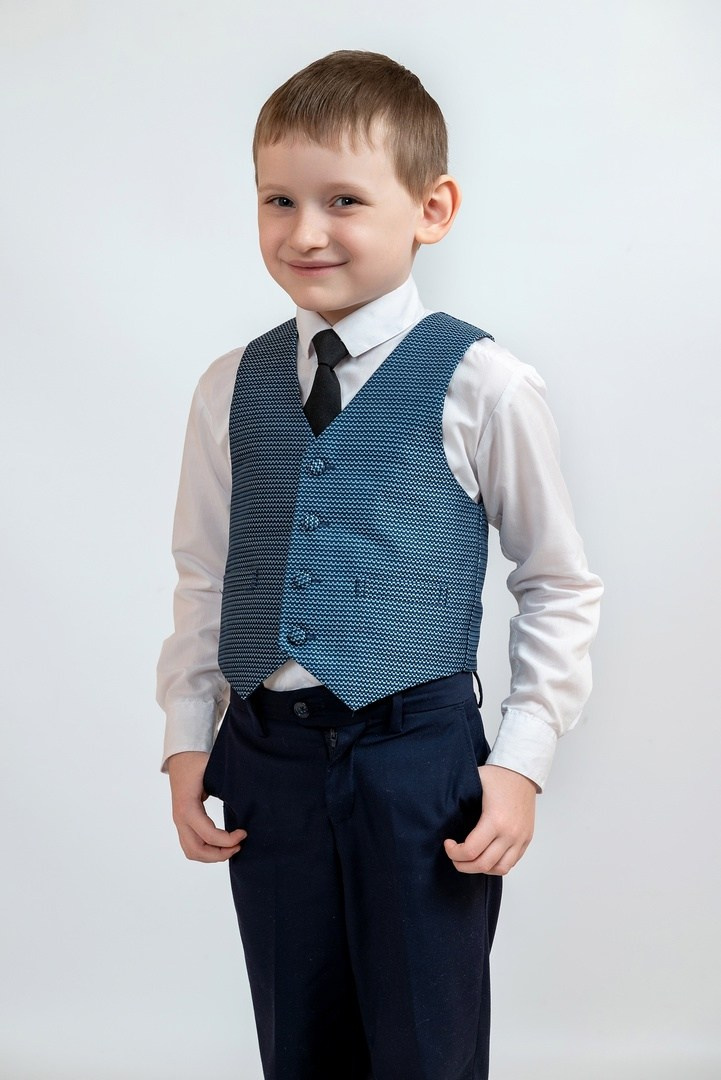 Молодой человек в жилетке и в галстуке фотографируется на Выпускной альбом.