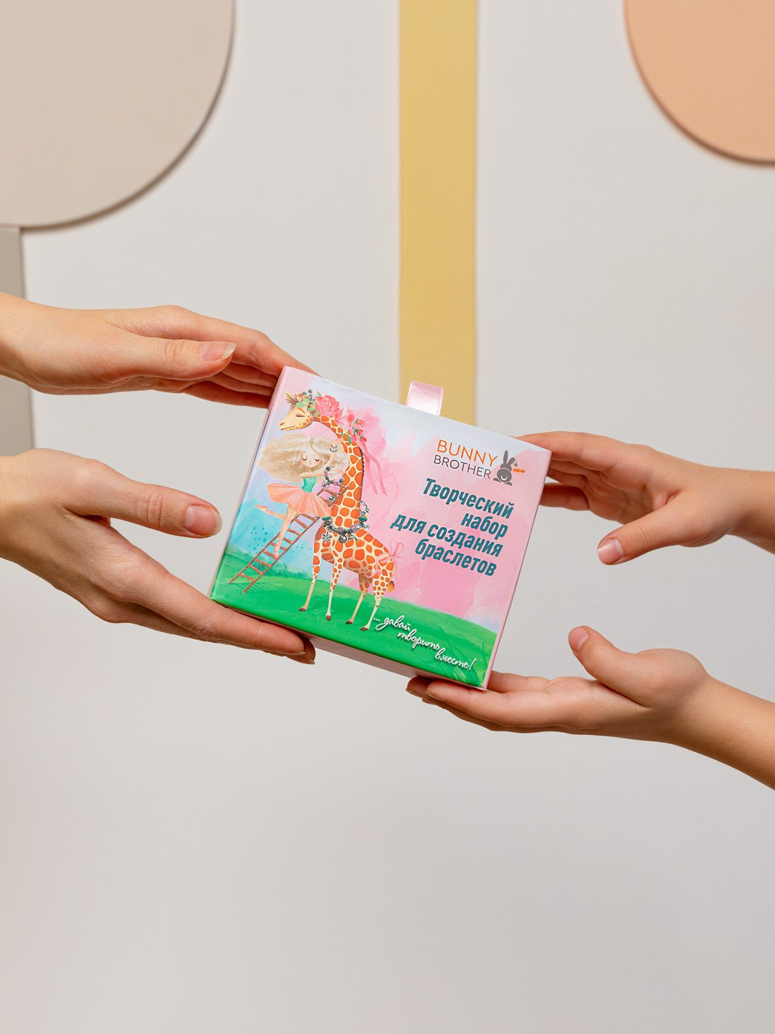 Бумажную коробку с набором для детского творчества держат 4 руки.